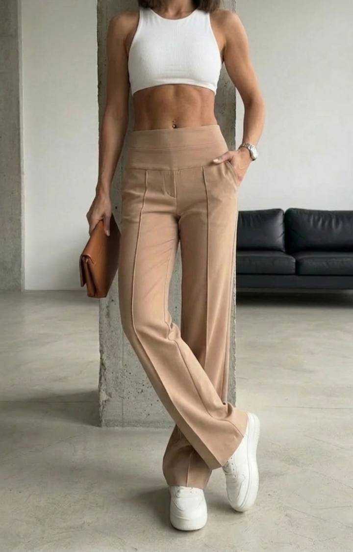 Person wearing a white crop top and beige high-waisted pants in an indoor setting.